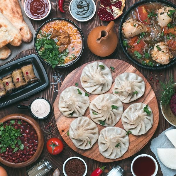 View from above of georgian cuisine on brown wooden table. Traditional georgian cuisine and food - khinkali, kharcho, chahokhbili, phali, lobio and local sauces - tkemali, satsebeli, adzhika. Top view